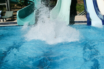 Water Slide Plunge. A person is captured mid-air as they splash into a pool after sliding down a...