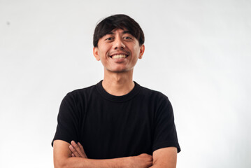 A smiling Asian man in a black t-shirt stands confidently with arms crossed against a plain white background, ideal for professional headshots, personal branding, or business profile content