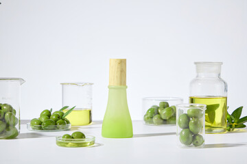 Several lab glassware scattered arranged on white table, an unlabeled green cosmetic bottle with wooden cork. Front view shot on white background, mockup for advertising