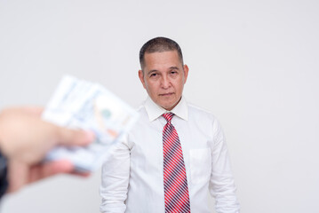 A middle aged professional ponders over taking a significant amount of cash. Potential bribery, payola or hush money. Isolated on a white background.