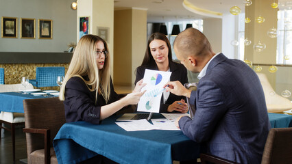 Close-up of a team discussing a budget plan with charts and data on a laptop. Ideal for showcasing professional consultations, financial planning, and collaborative work in a business setting.