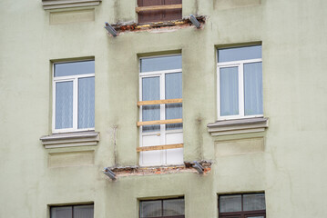 Damaged building facade with dismantled balcony, structural repair and restoration in progress, renovation and reinforcement. Structural repair and concrete reinforcement of historic building facade