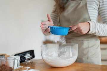 Woman Adding Flour to Mixing Bowl for Baking in Kitchen