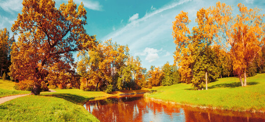 Obraz premium Autumn landscape scene - autumn trees near the river in sunny October park lit by sunlight, vintage tones