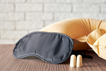 Black sleep mask and foam earplugs on a wooden surface. These items are perfect for promoting a...