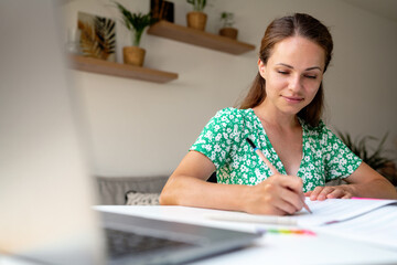 Young adult woman studying at a desk at home.