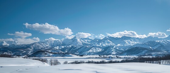 Obraz premium Majestic Snowy Mountains Bathed in Sunlight under a Clear Blue Sky with Wispy Clouds