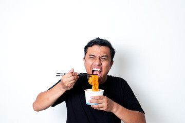 Fototapeta premium Asian adult man wearing a black t-shirt posing eating Korean specialty food odeng isolated white background
