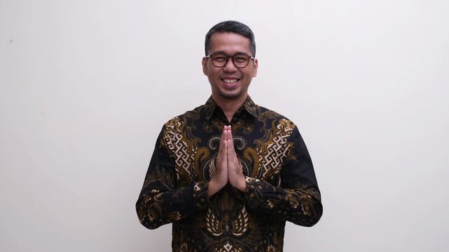 A man smiling friendly at the camera while doing welcoming pose