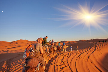 Tourists riding camels, smiling, in the Sahara Desert