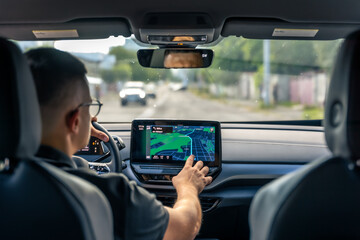Man touching screen of a GPS navigation system in his car.