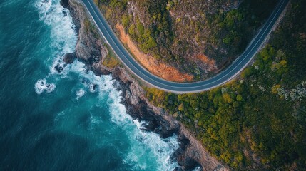 Aerial View of Coastal Road Winding Along Rugged Cliffside with Waves Crashing Against the Shoreline