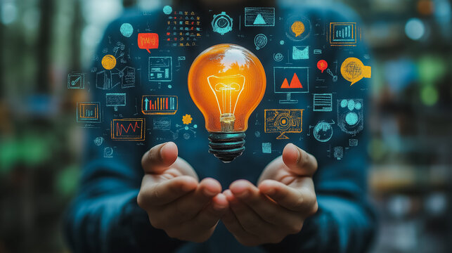 A person is holding a light bulb in their hand, surrounded by various symbols and images. Concept of creativity and innovation, as the light bulb is often associated with new ideas and inspiration