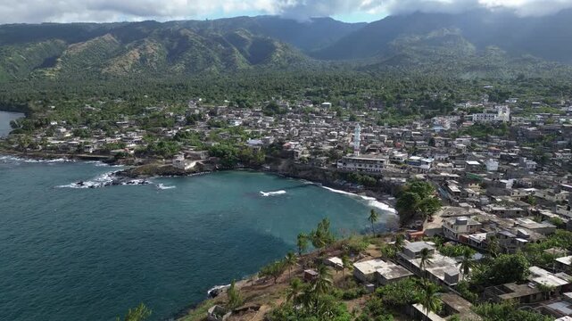 Aerial view of Domoni town in Anjouan volcanic island in the Comoro Islands Indian Ocean, drone approaching the bay village built around the main mosque