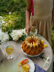 Chamomile flowers, books, glass teapot and cup with herbal tea on table in garden, natural background. summer season. relax time. useful calming tea. tea party outdoor