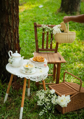 Chamomile flowers, books, glass teapot and cup with herbal tea on table in garden, natural background. summer season. relax time. useful calming tea. tea party outdoor