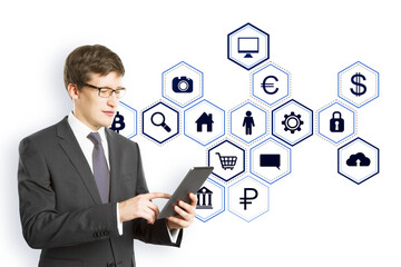 Businessman in a suit using a tablet with blue virtual holographic icons floating on a white background, representing digital data