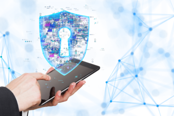 Hands holding a tablet with a holographic shield displaying a keyhole, set against a white background. Concept of digital security and data protection