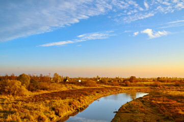 Obraz premium Autumn landscape. Small village at the bank of the river at the autumn evening in bright sunlight - autumn rural landscape in warm tone