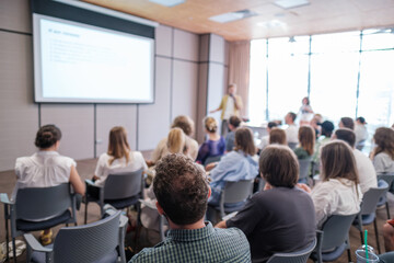 Fototapeta premium Attendees sit attentively as speaker presents during business conference. Bright, modern meeting room enhances learning experience while promoting collaboration and focus among participants.