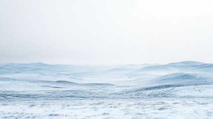 Obraz premium A serene winter landscape with rolling hills covered in snow and a soft, misty atmosphere.