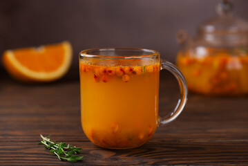 Hot sea buckthorn tea with orange, ginger, thyme and cinnamon in glass cups on a brown background. Herbal vitamin c tea.