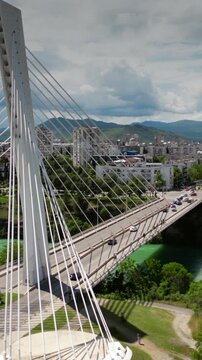 Aerial orbiting shot of the Millennium Bridge, a cable-stayed bridge and the Moracha river in Podgorica, Montenegro, vertical video