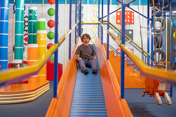 happy boy with emotions goes down the slide attraction. Family weekend