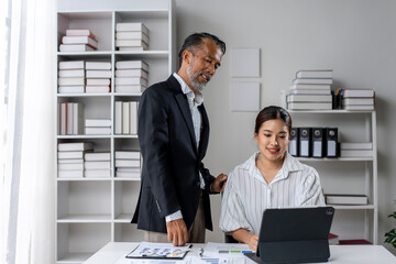 A man and a woman are sitting at a desk with a laptop