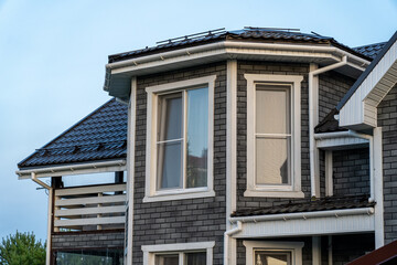 A modern house showcases its stylish design with bright windows and a sloped roof as dusk approaches