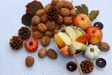 Autumn still life with apples, nuts, red leaves and candles on a table. Textured background with space for text. 