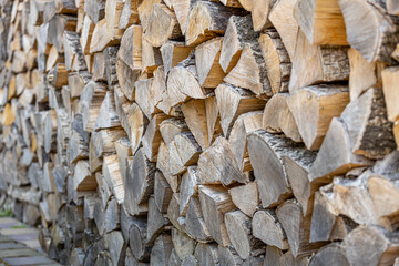 Background of stacked chopped wood logs. Pile of wood logs ready for winter. Wooden stumps, firewood stacked in heap