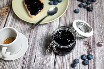 Healthy breakfast with homemade blueberries jam. Glass jar with homemade blueberries jam, slice of bread with jam