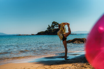 A red hair caucasian girl demonstrates ballet moves on the beach.