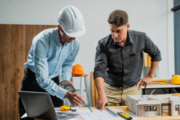 A Caucasian middle-aged male engineer contractor and an Italian architect engineer are seated at a...