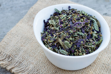 Dried basil in a bowl on a wooden background.  Spice, mixture of green and purple basil.