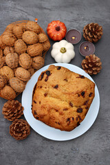 Raisin fruit cake dessert traditional pastry dried fruits, nuts, apples, cones and candles on dark grey background with copy space. Autumn menu ideas. 