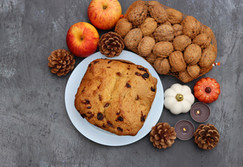 Raisin fruit cake dessert traditional pastry dried fruits, nuts, apples, cones and candles on dark grey background with copy space. Autumn menu ideas. 