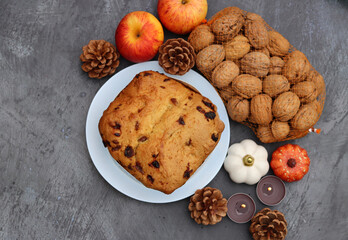 Raisin fruit cake dessert traditional pastry dried fruits, nuts, apples, cones and candles on dark grey background with copy space. Autumn menu ideas. 