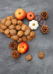 Autumn background. Apples, nuts, fir cones, candles and autumn leaves on dark textured table with space for text.  