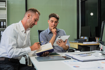 Caucasian middle-aged male businessperson and an Italian accountant are seated at a desk, engaging in a professional meeting, discussing various aspects of technology and innovation in their fields.