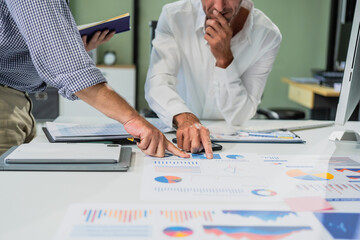 Caucasian middle-aged male businessperson and an Italian accountant are seated at a desk, engaging...