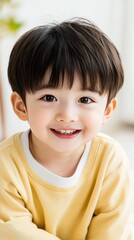 Obraz premium A cheerful three-year-old boy wearing a yellow sweater and white T-shirt beams with joy in a sunlit living room