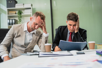 Caucasian middle-aged male businessperson and an Italian accountant are seated at a desk, engaging in a professional meeting, discussing various aspects of technology and innovation in their fields.