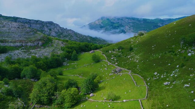 Fog in the spring landscape of pastures and Pasiegas cabins in the Natural Park of the Collados del As&oacute;n. Aerial view from a drone. Hills of Ason Natural Park. Soba Valley, Cantabria, Spain, Europe