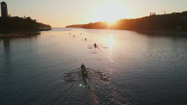 Aerial view. A rowing team of young men and women powers through the water in an early morning practice session, captured by a drone over Nova Scotia ocean bay. Halifax Canada