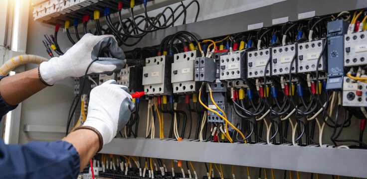 Checking the electrical system, an electrician is using an electric meter to check the electrical system at a control cabinet. for safety