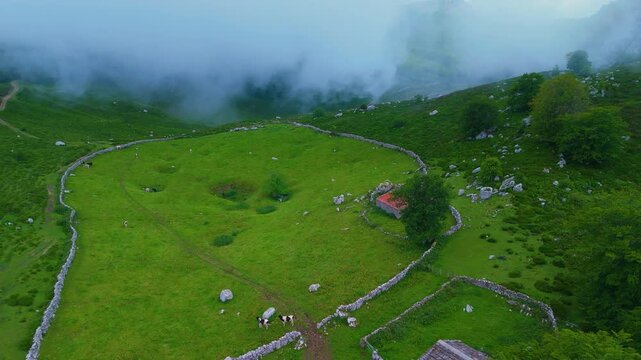 Fog in the spring landscape of pastures and Pasiegas cabins in the Natural Park of the Collados del As&oacute;n. Aerial view from a drone. Hills of Ason Natural Park. Soba Valley, Cantabria, Spain, Europe