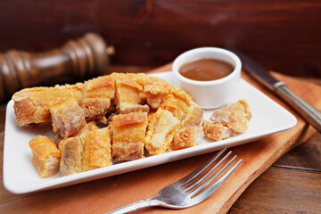 Thai food. Crispy fried pork belly cut into pieces on a wooden table.