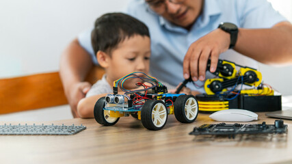 A boy are learning to build robot toys with their dad in the living room. Robot model, learning,...